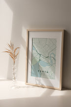 Perth, Western Australia, Australia map print in the Forest theme in a light wooden frame on a shelf beside a glass vase