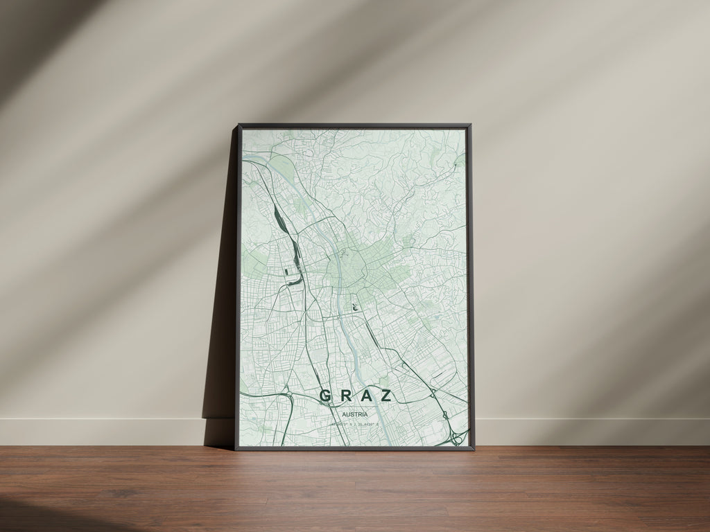 Graz map print in the Forest theme in a black frame on a wooden surface against a pale wall