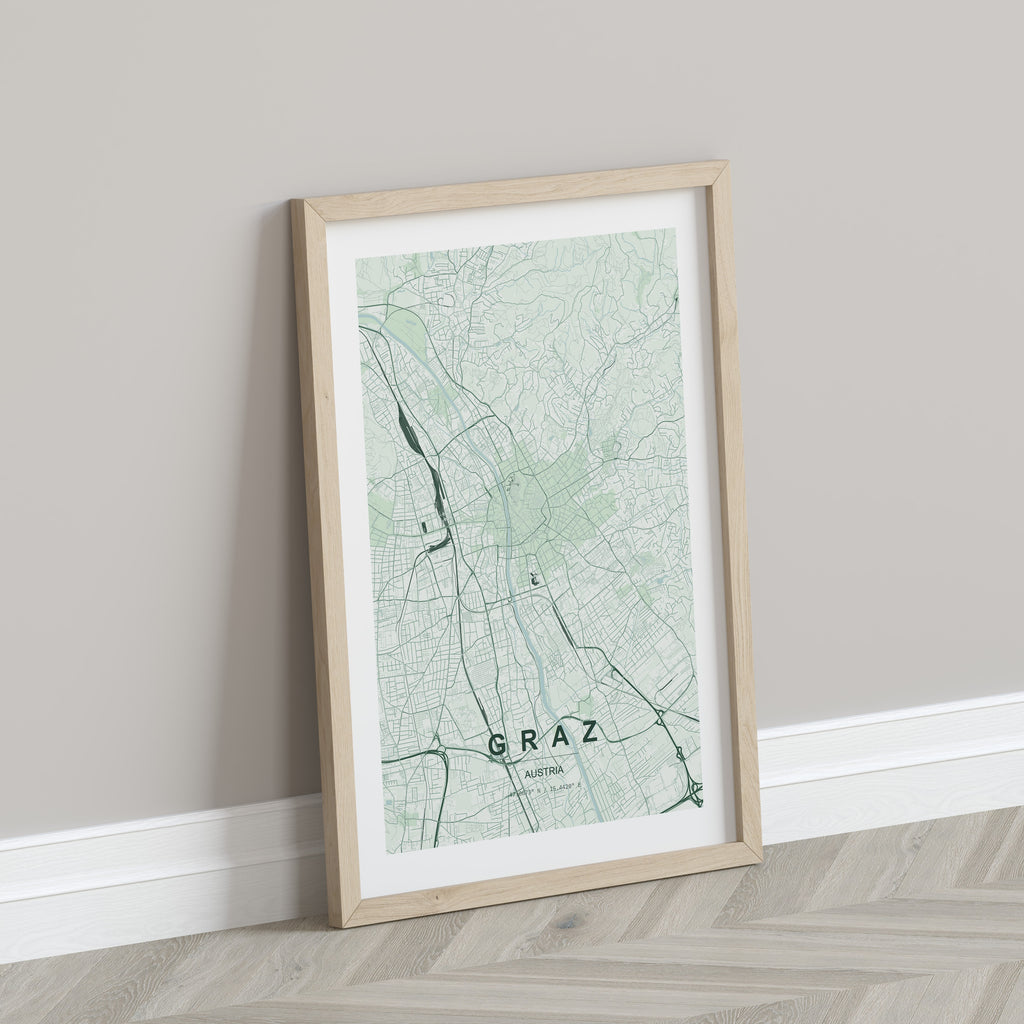 Graz map print in the Forest theme in a light wooden frame leaning against a pale wall