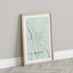 Graz map print in the Forest theme in a light wooden frame leaning against a pale wall