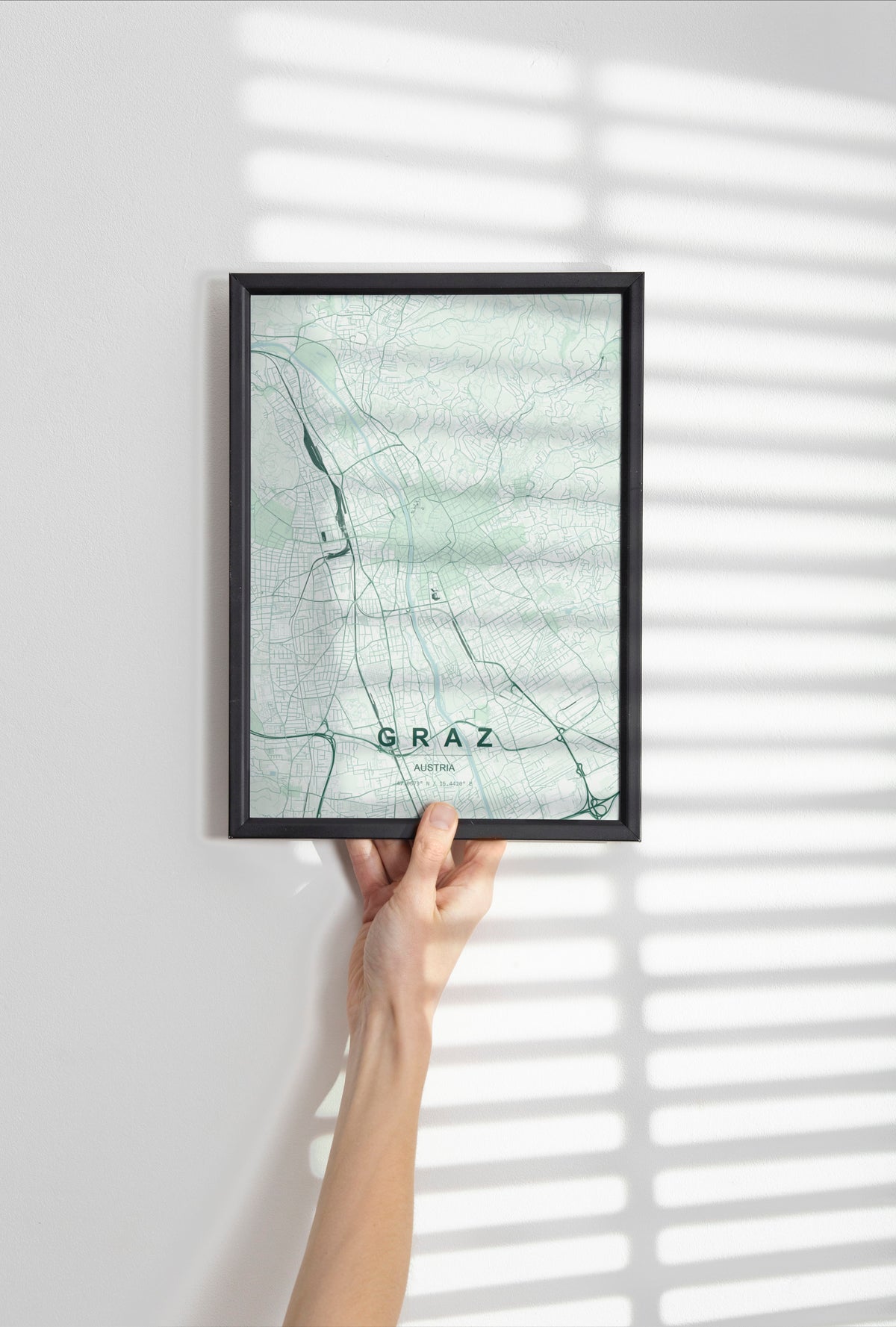 Graz map print in the Forest theme in a black frame held against a pale wall