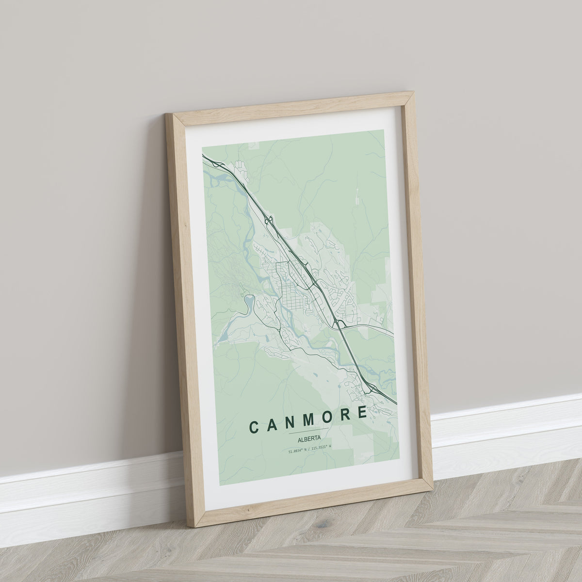 Canmore, Alberta, Canada map print in the Forest theme in a light wooden frame leaning against a pale wall