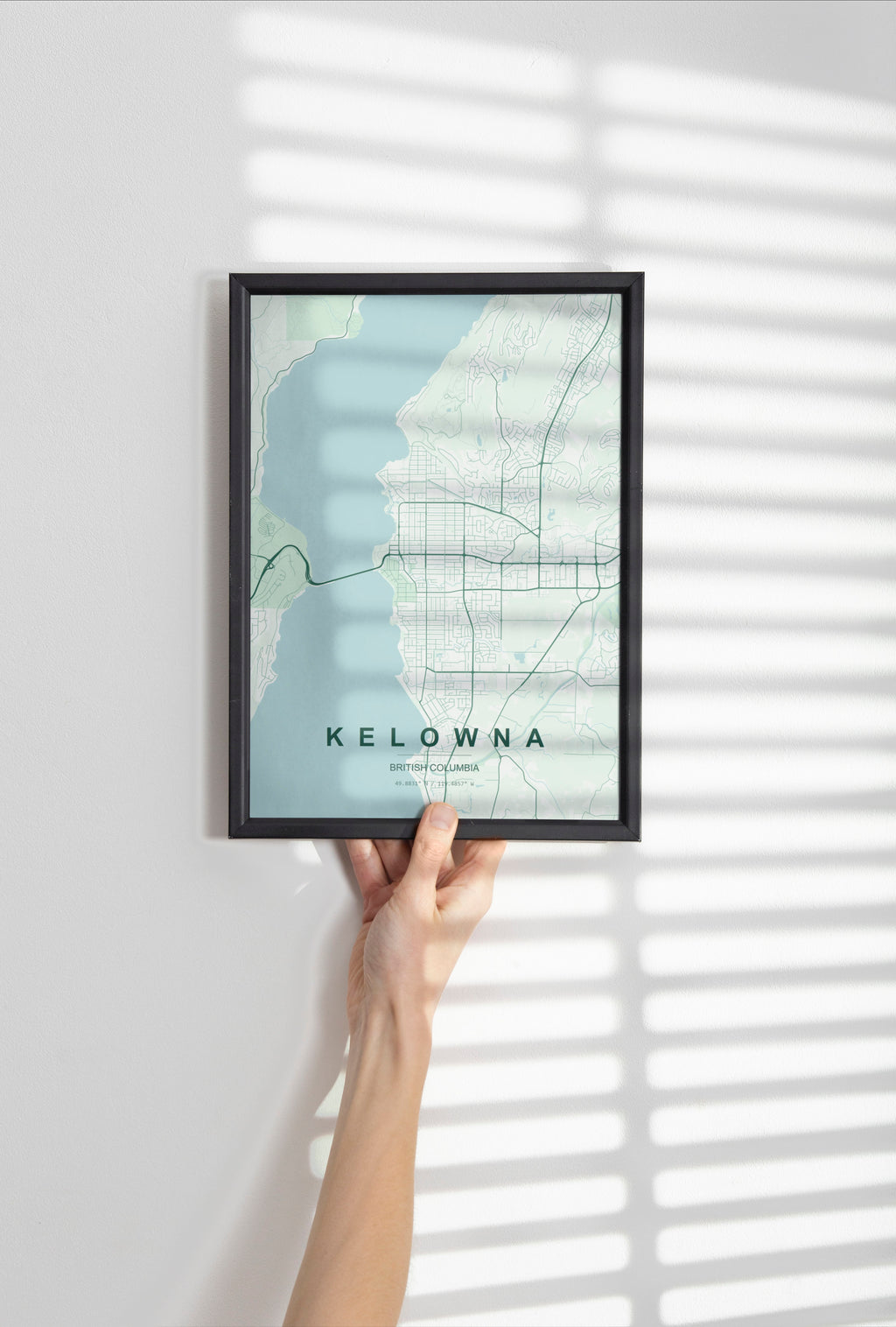 Kelowna, British Columbia, Canada map print in the Forest theme in a black frame held against a pale wall