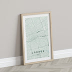 London, Ontario, Canada map print in the Forest theme in a light wooden frame leaning against a pale wall