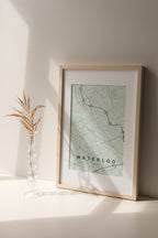 Waterloo, Ontario, Canada map print in the Forest theme in a light wooden frame on a shelf beside a glass vase