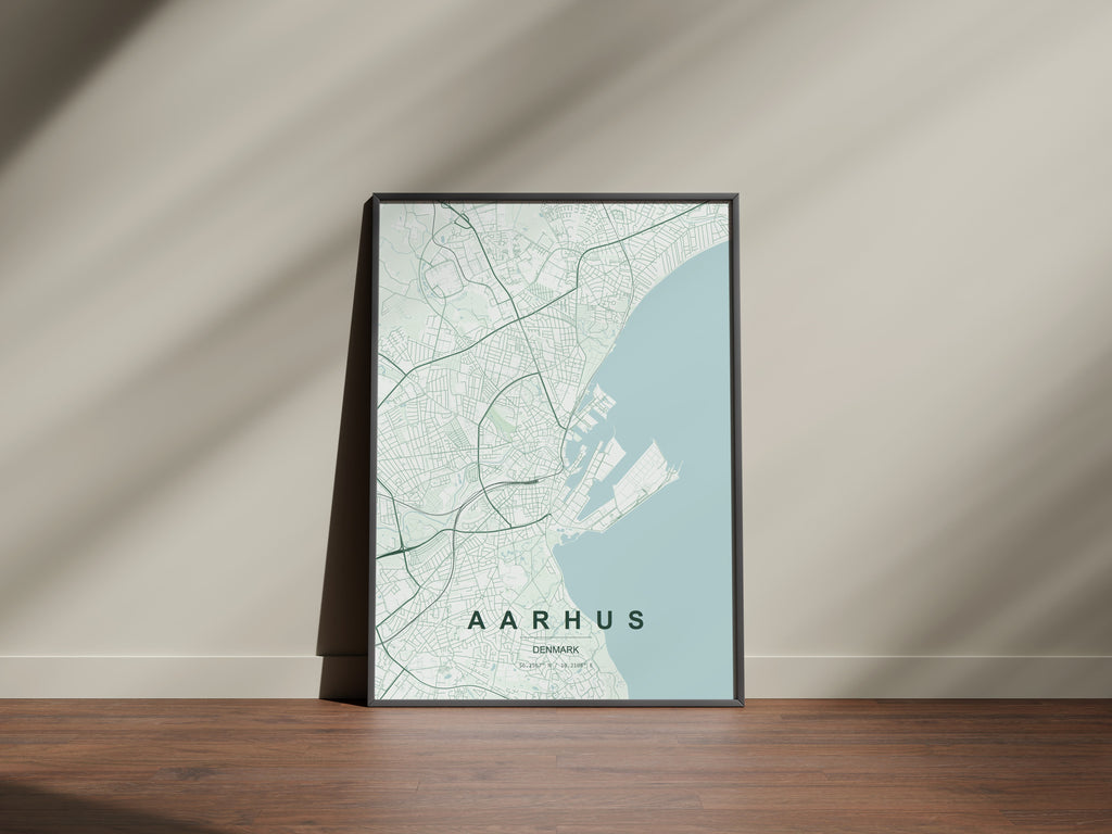 Aarhus map print in the Forest theme in a black frame on a wooden surface against a pale wall