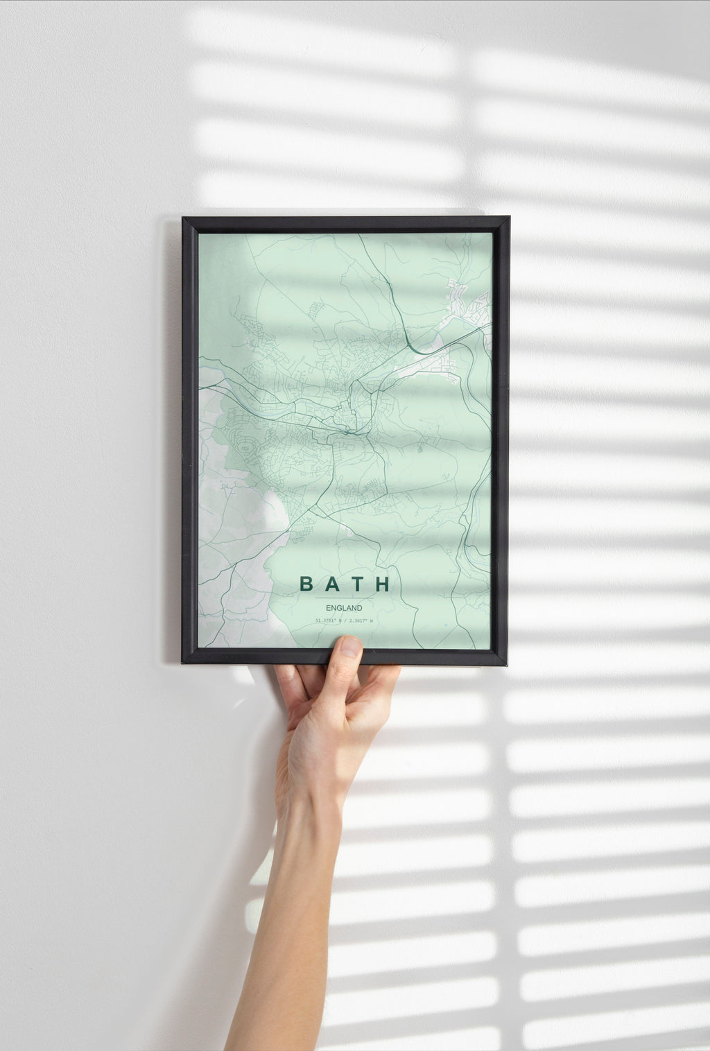 Example artwork, not your finished custom map: Bath map print in the Forest theme in a black frame held against a pale wall