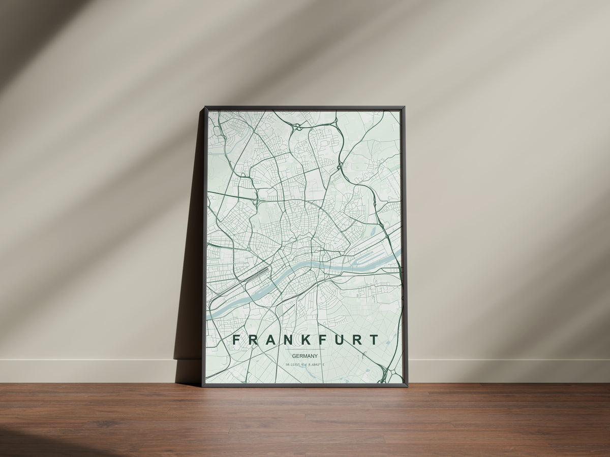 Frankfurt map print in the Forest theme in a black frame on a wooden surface against a pale wall