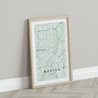 Munich map print in the Forest theme in a light wooden frame leaning against a pale wall