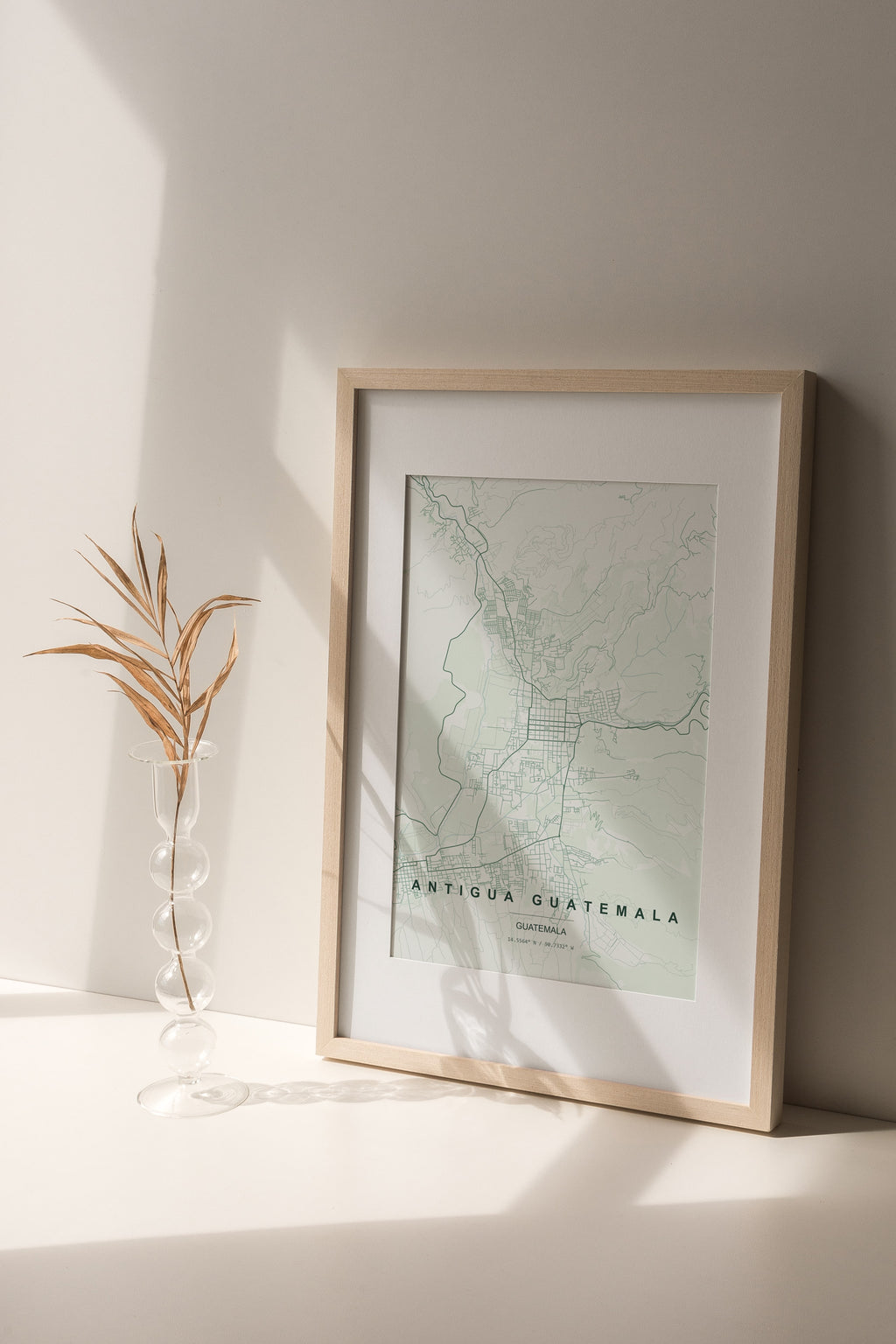 Antigua Guatemala, Guatemala map print in the Forest theme in a light wooden frame on a shelf beside a glass vase