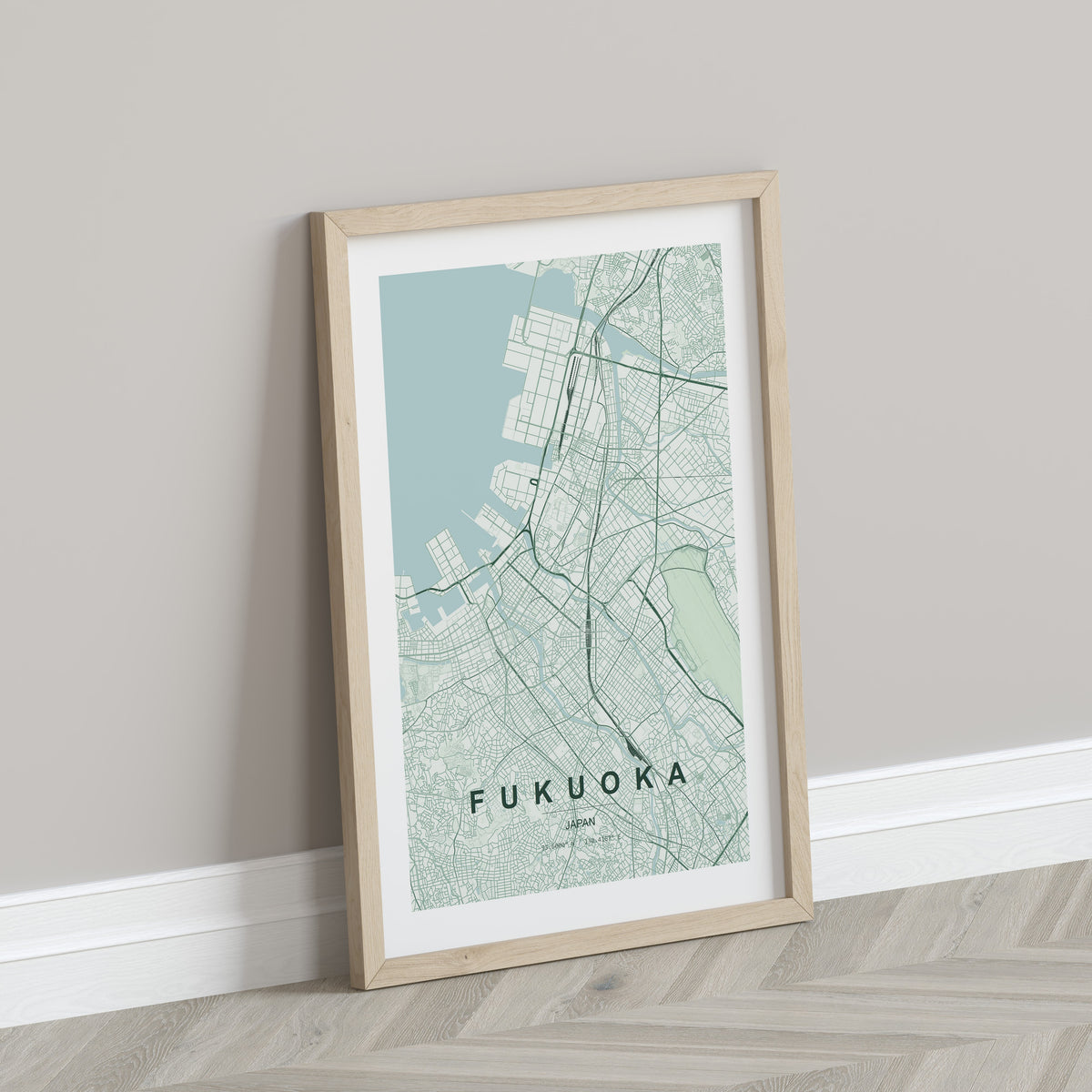 Fukuoka, Japan map print in the Forest theme in a light wooden frame leaning against a pale wall