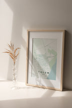 Tulum, Mexico map print in the Forest theme in a light wooden frame on a shelf beside a glass vase