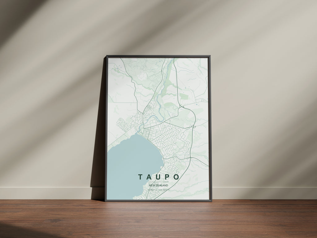 Taupō, New Zealand map print in the Forest theme in a black frame on a wooden surface against a pale wall