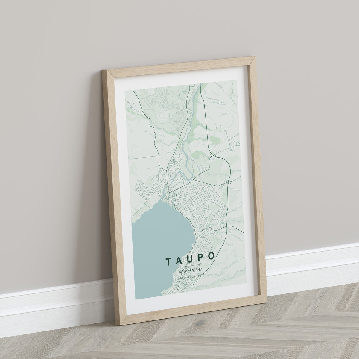 Taupō, New Zealand map print in the Forest theme in a light wooden frame leaning against a pale wall