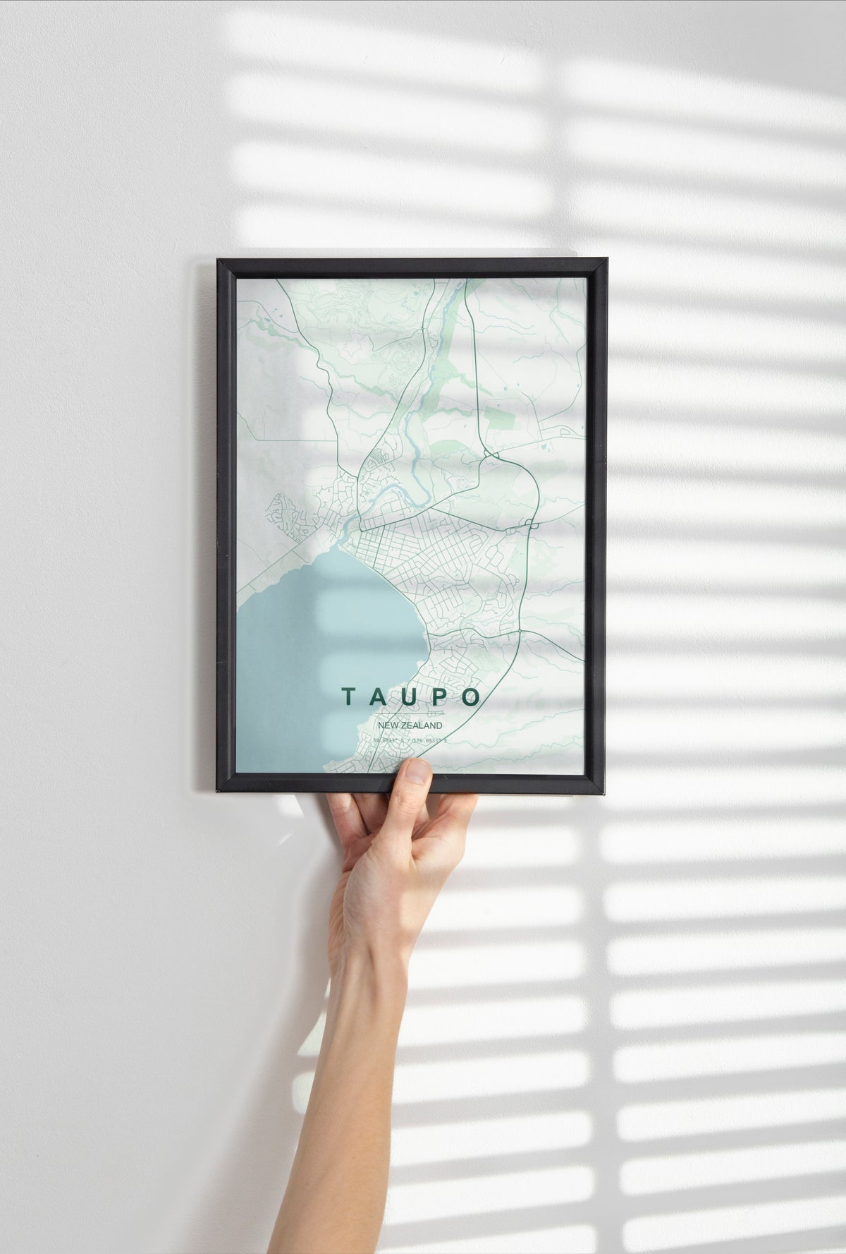 Taupō, New Zealand map print in the Forest theme in a black frame held against a pale wall