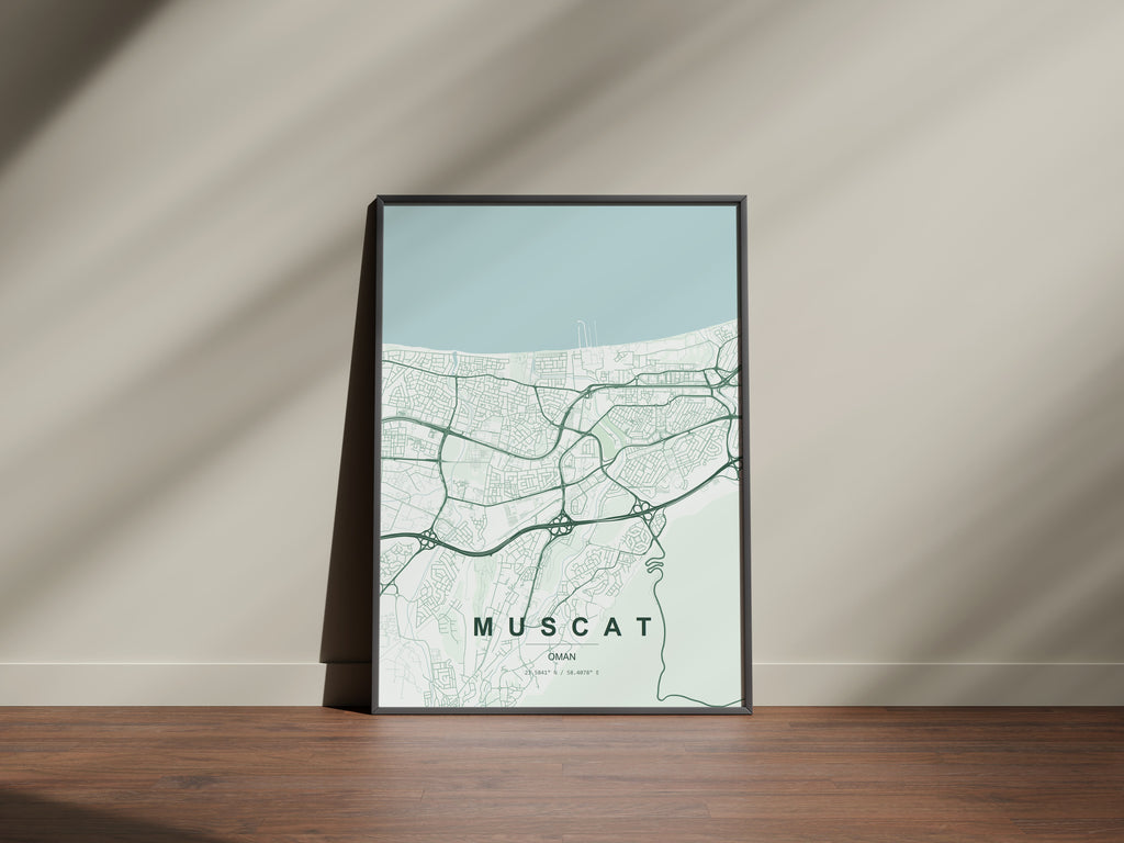 Muscat, Oman map print in the Forest theme in a black frame on a wooden surface against a pale wall