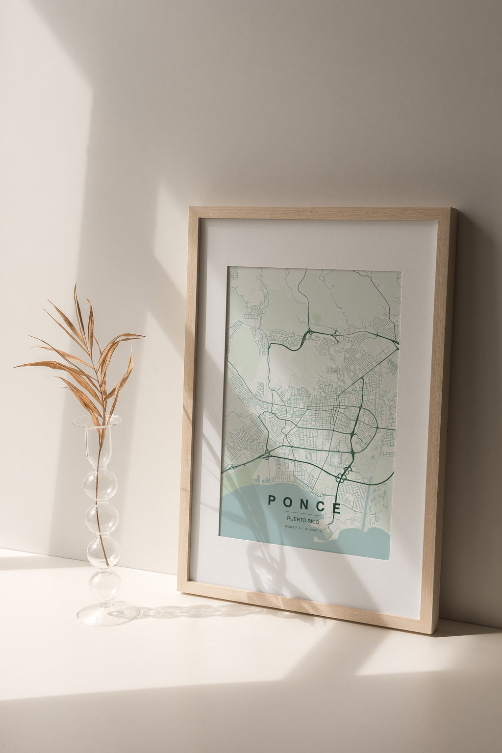Ponce, Puerto Rico, United States map print in the Forest theme in a light wooden frame on a shelf beside a glass vase