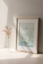 Ponce, Puerto Rico, United States map print in the Forest theme in a light wooden frame on a shelf beside a glass vase