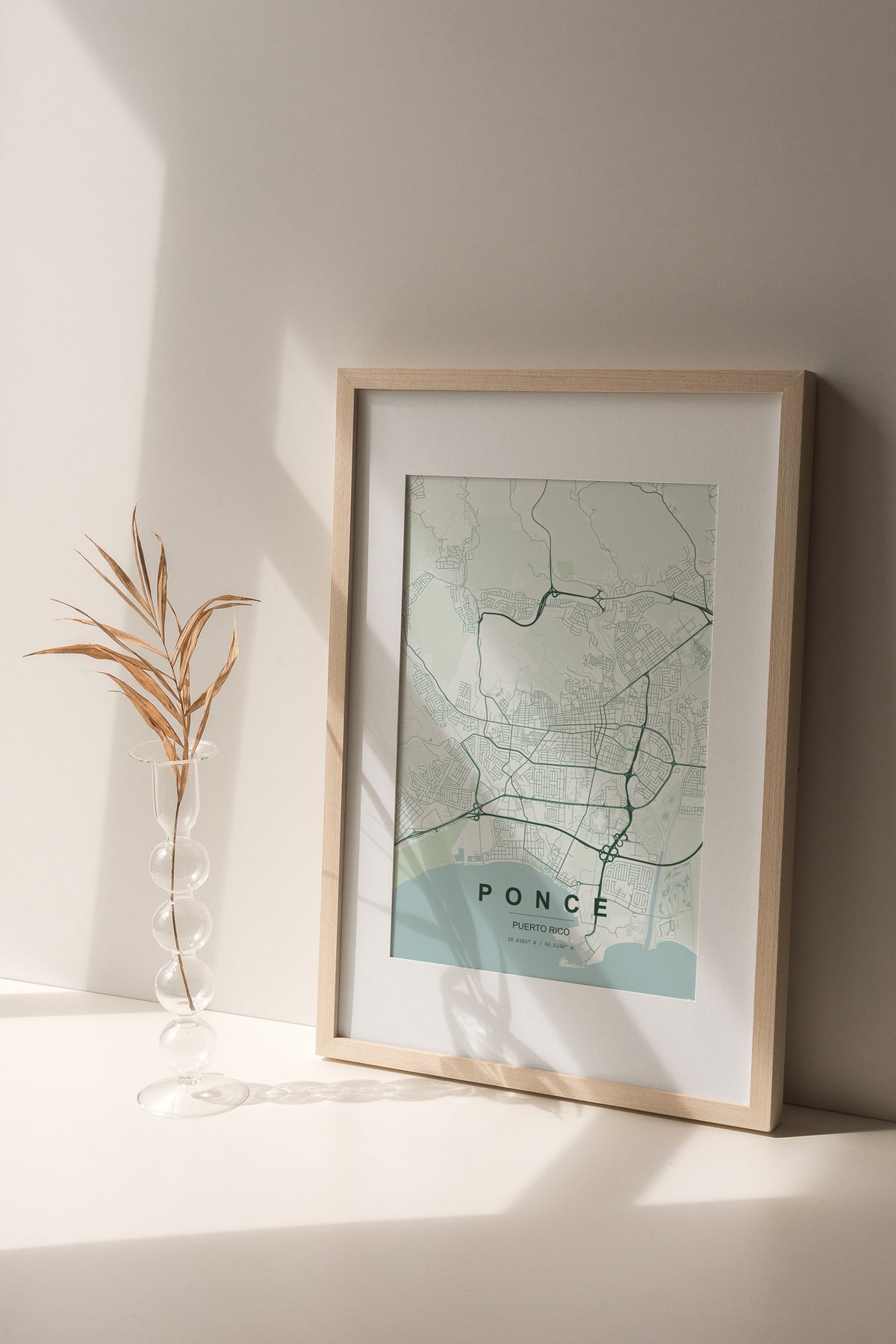 Ponce, Puerto Rico, United States map print in the Forest theme in a light wooden frame on a shelf beside a glass vase