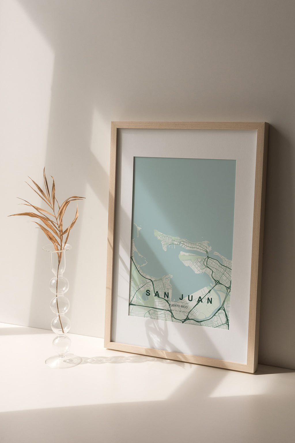 San Juan, Puerto Rico, United States map print in the Forest theme in a light wooden frame on a shelf beside a glass vase