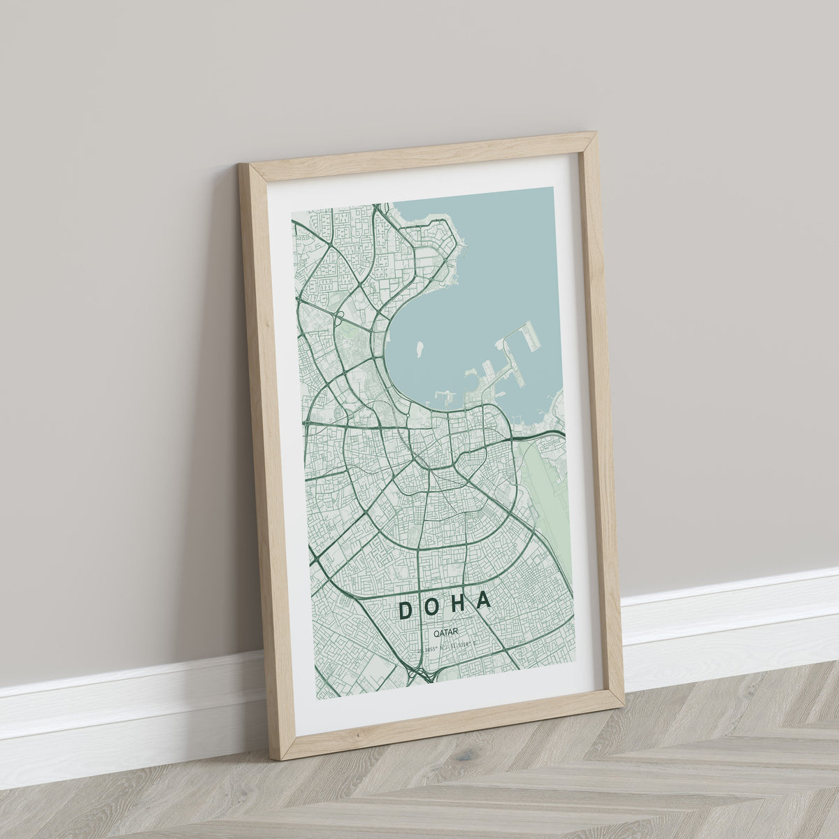 Doha, Qatar map print in the Forest theme in a light wooden frame leaning against a pale wall