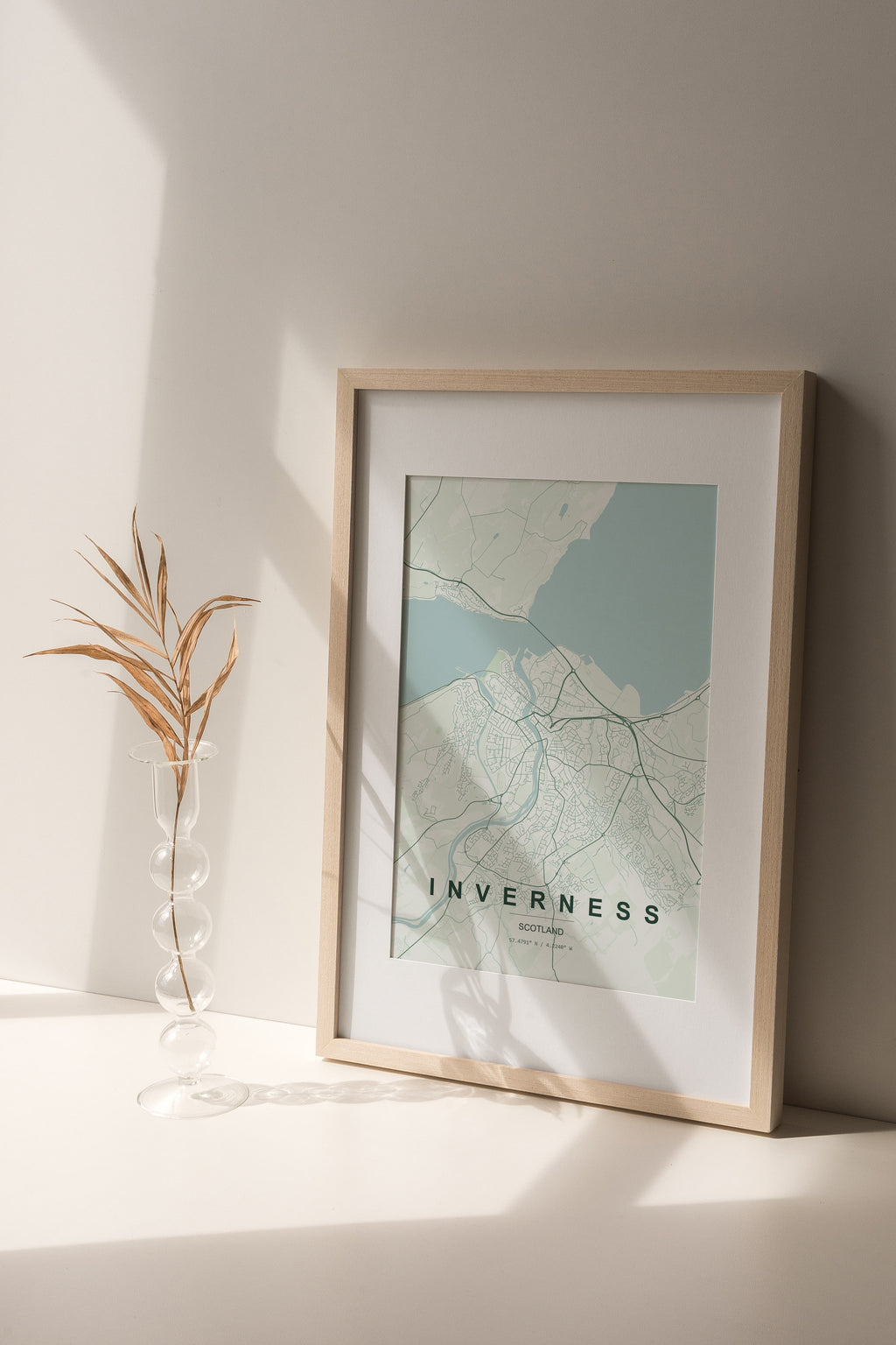 Inverness, Scotland, United Kingdom map print in the Forest theme in a light wooden frame on a shelf beside a glass vase