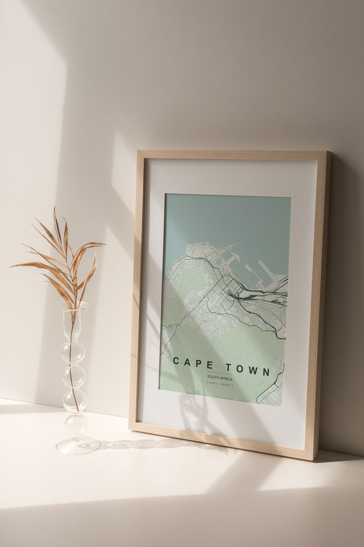Cape Town, Western Cape, South Africa map print in the Forest theme in a light wooden frame on a shelf beside a glass vase