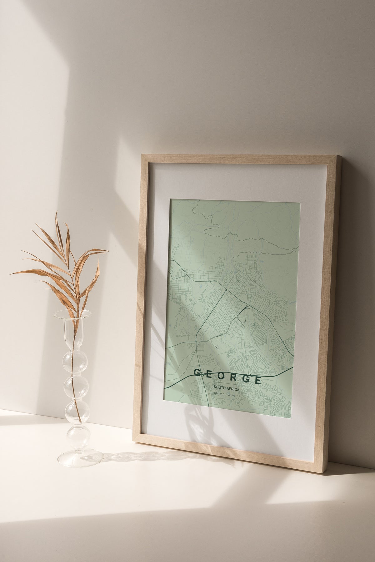 George, Western Cape, South Africa map print in the Forest theme in a light wooden frame on a shelf beside a glass vase