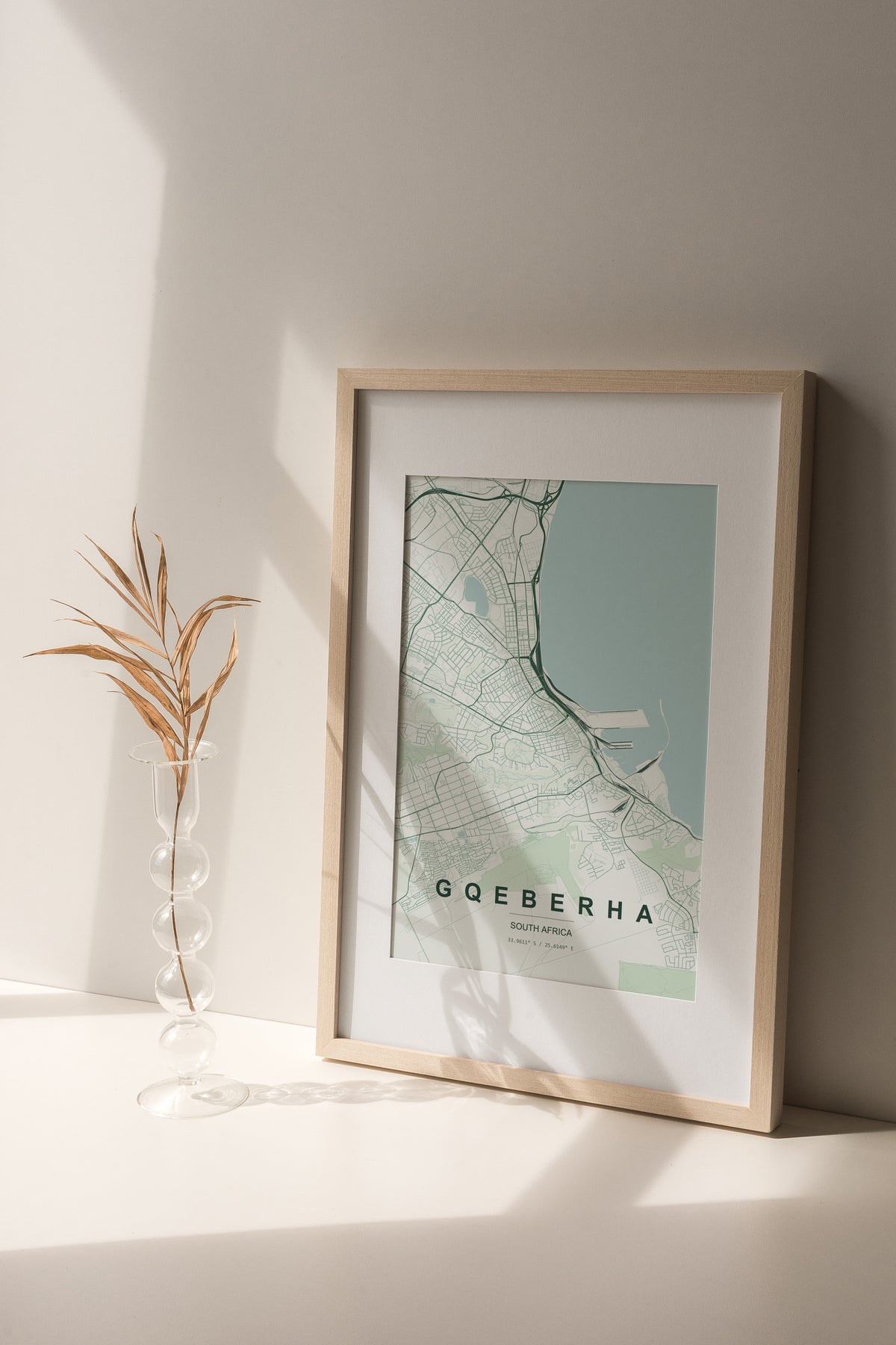 Gqeberha, Eastern Cape, South Africa map print in the Forest theme in a light wooden frame on a shelf beside a glass vase