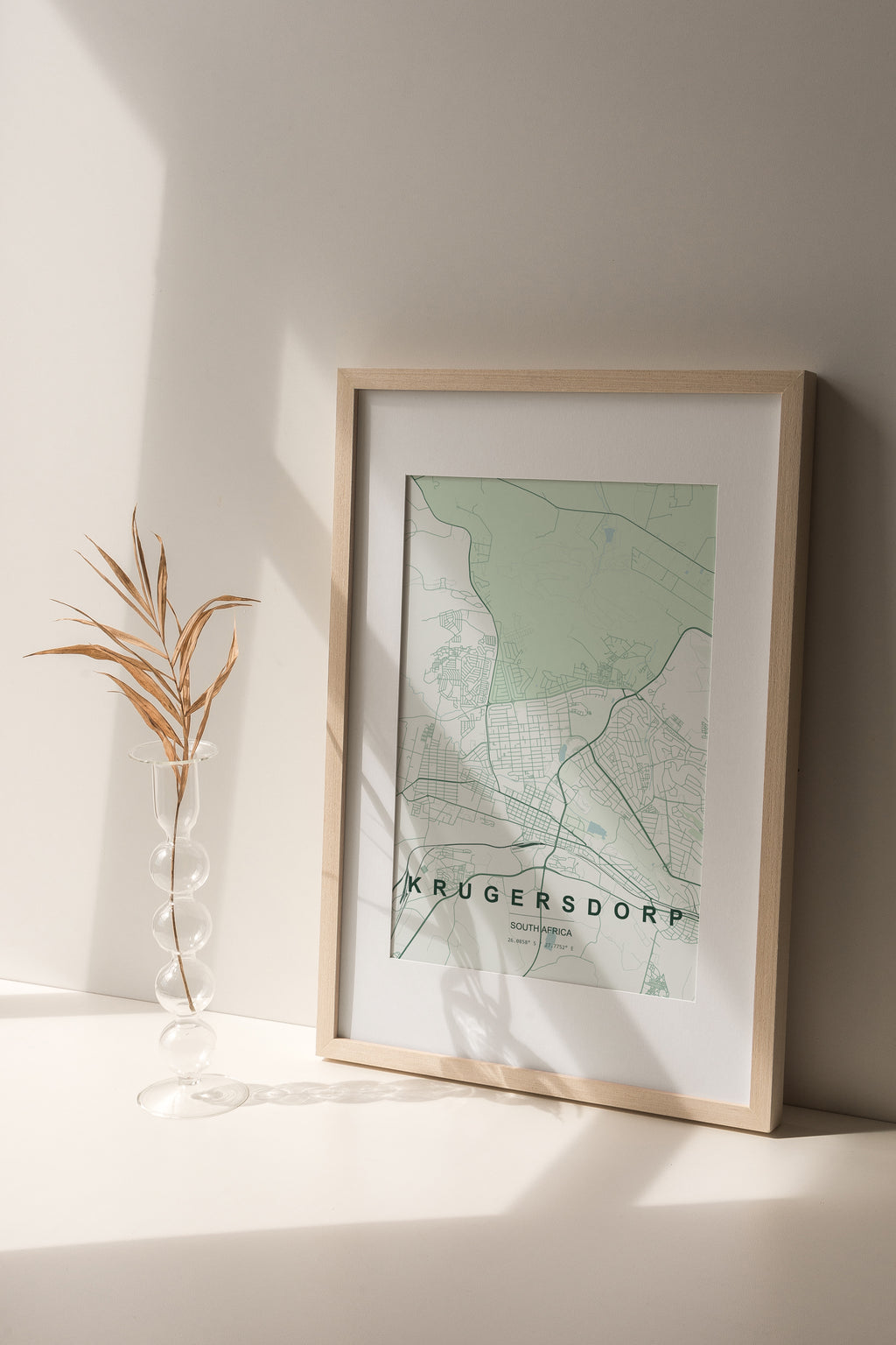 Krugersdorp, Gauteng, South Africa map print in the Forest theme in a light wooden frame on a shelf beside a glass vase