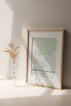 Krugersdorp, Gauteng, South Africa map print in the Forest theme in a light wooden frame on a shelf beside a glass vase