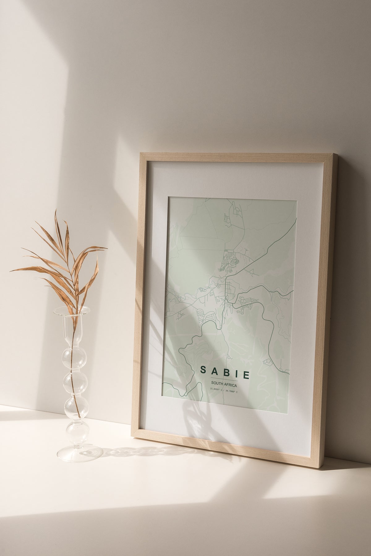 Sabie, Mpumalanga, South Africa map print in the Forest theme in a light wooden frame on a shelf beside a glass vase