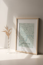 London map print in the Forest theme in a light wooden frame on a shelf beside a glass vase