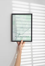 Flagstaff map print in the Forest theme in a black frame held against a pale wall