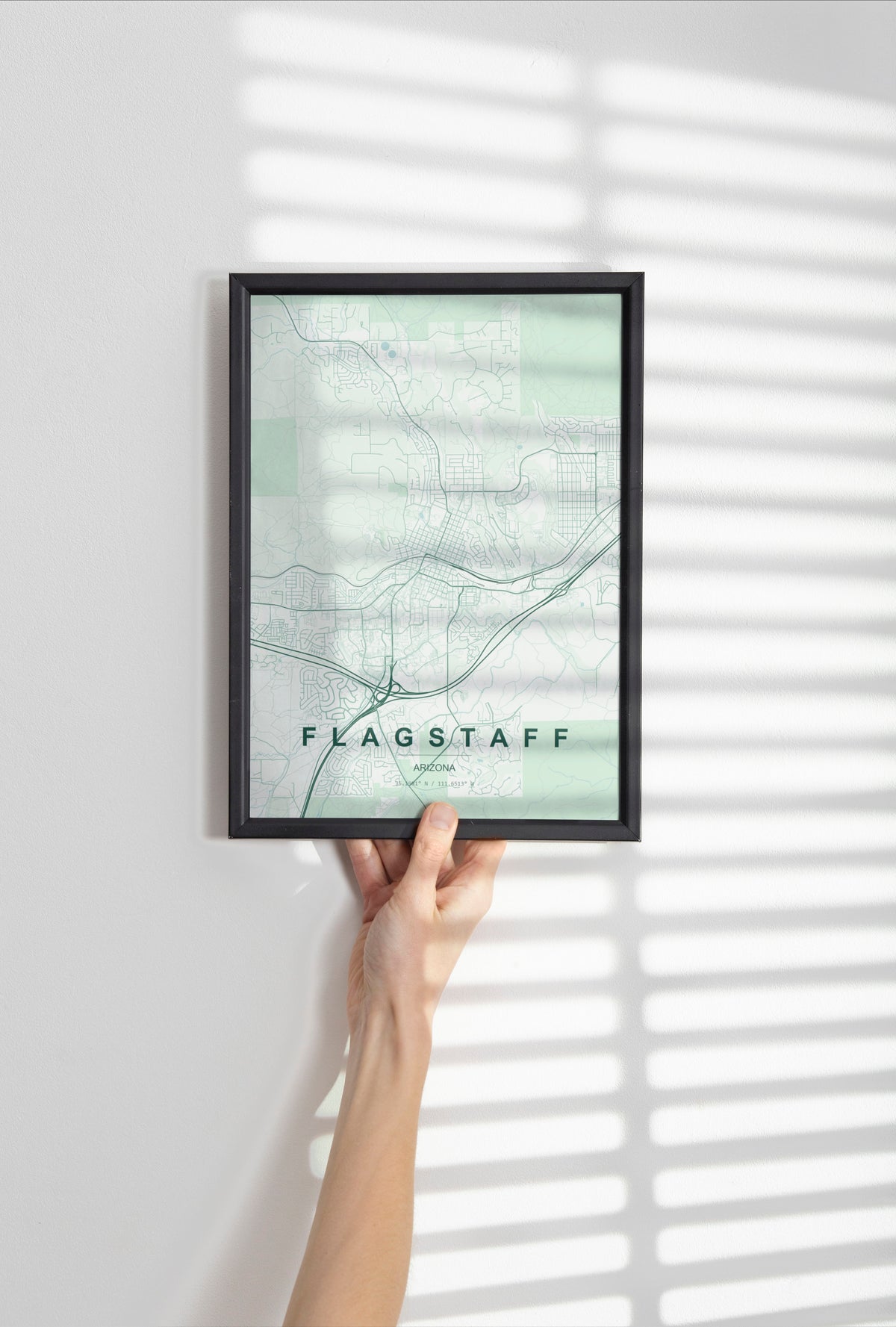 Flagstaff map print in the Forest theme in a black frame held against a pale wall