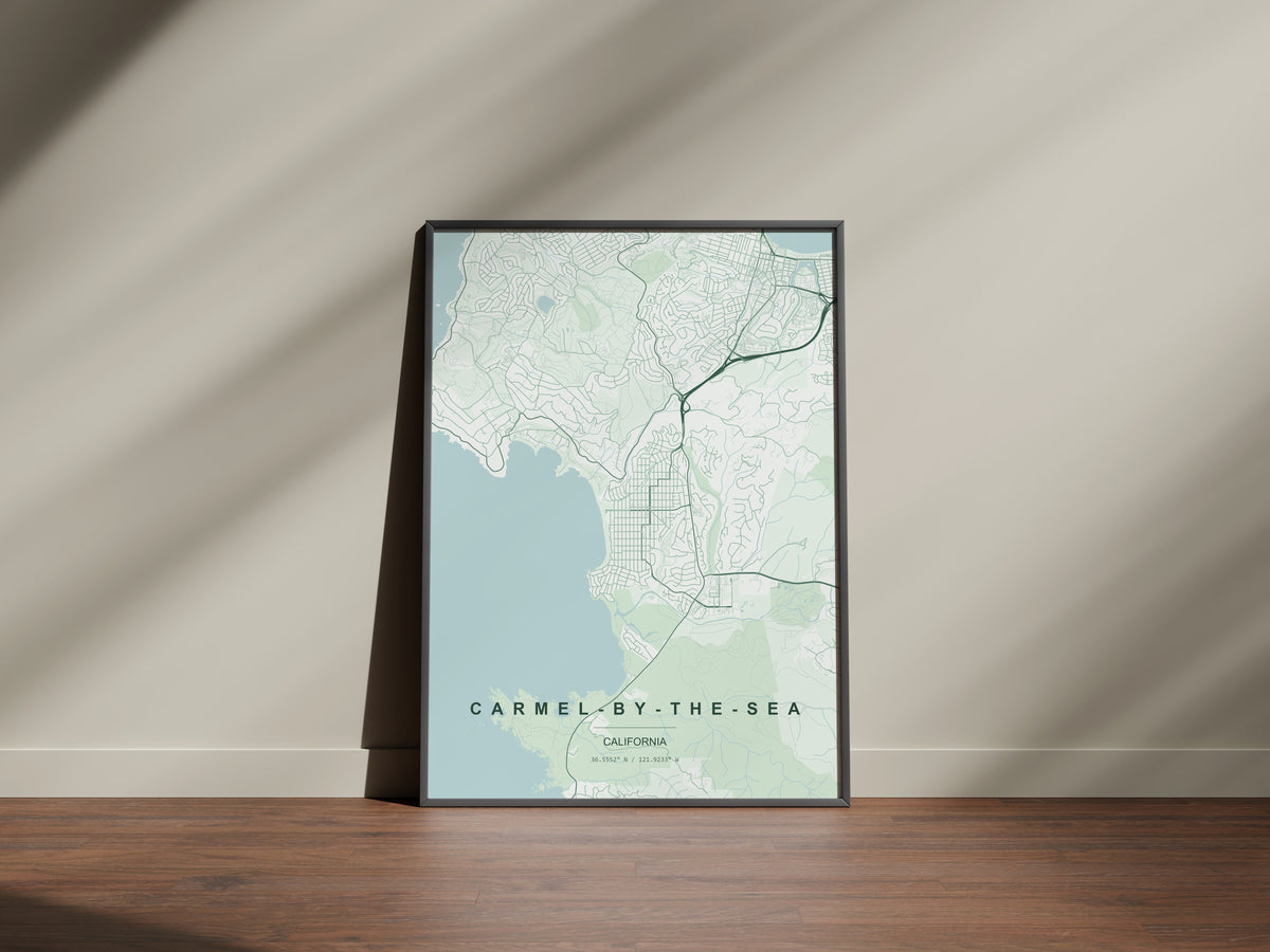 Carmel-by-the-Sea map print in the Forest theme in a black frame on a wooden surface against a pale wall