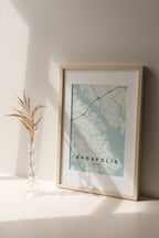Annapolis map print in the Forest theme in a light wooden frame on a shelf beside a glass vase