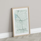 Syracuse map print in the Forest theme in a light wooden frame leaning against a pale wall
