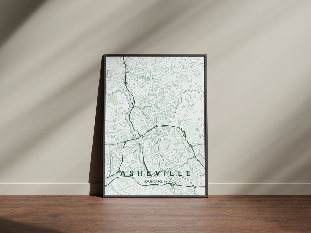 Asheville map print in the Forest theme in a black frame on a wooden surface against a pale wall