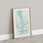 Olympia map print in the Forest theme in a light wooden frame leaning against a pale wall