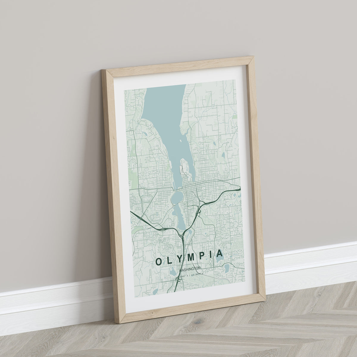Olympia map print in the Forest theme in a light wooden frame leaning against a pale wall