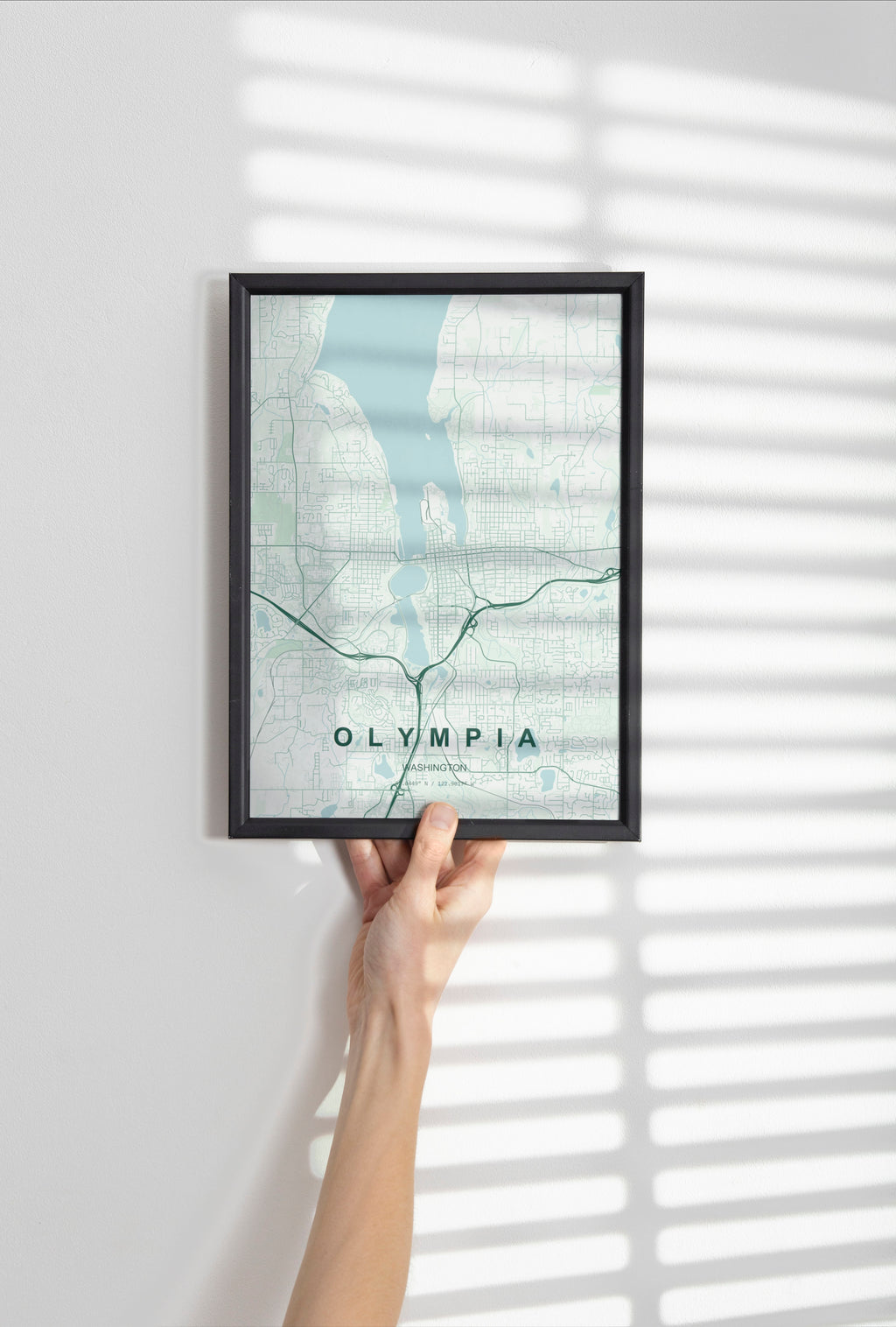 Olympia map print in the Forest theme in a black frame held against a pale wall