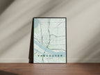 Vancouver map print in the Forest theme in a black frame on a wooden surface against a pale wall