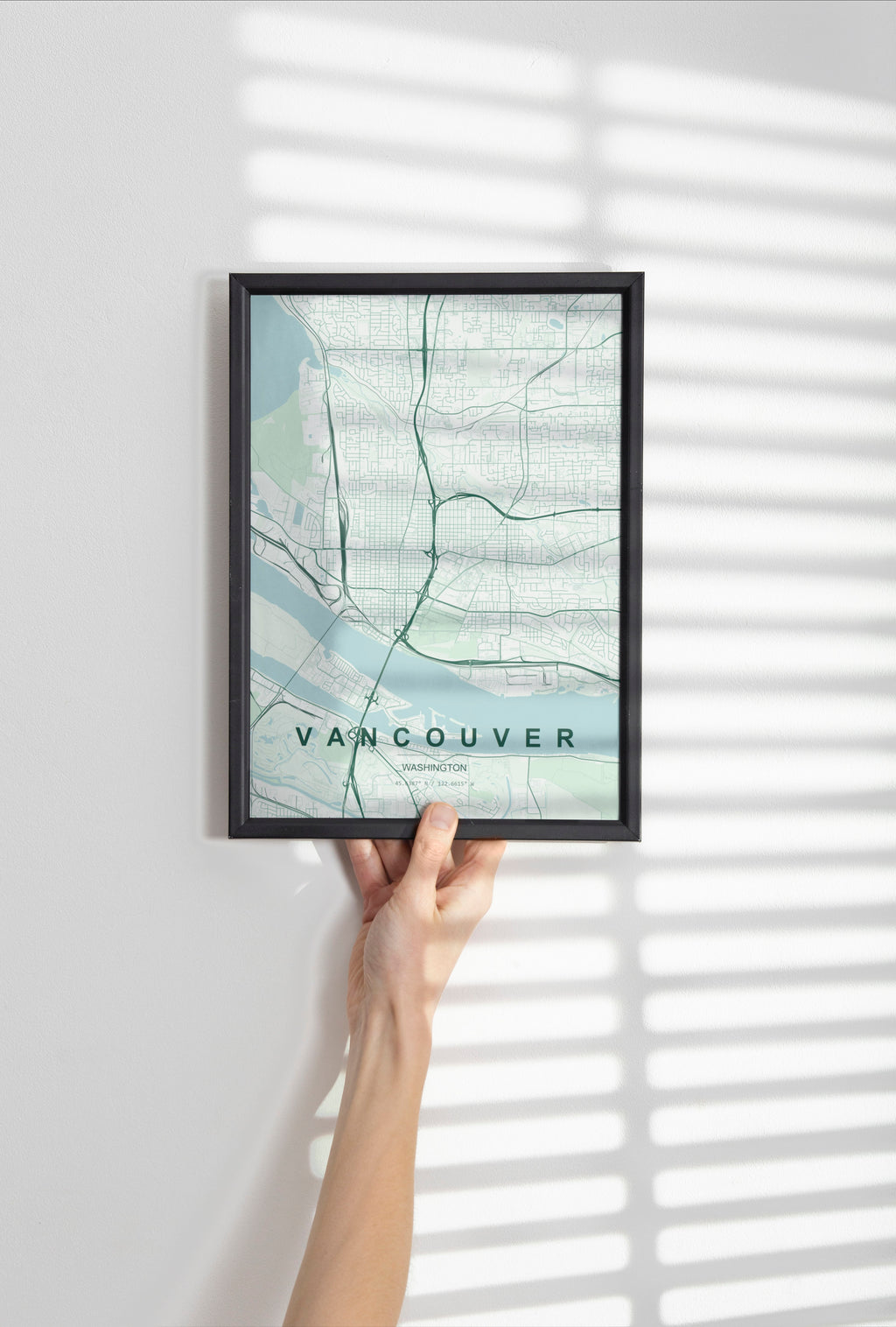 Vancouver map print in the Forest theme in a black frame held against a pale wall