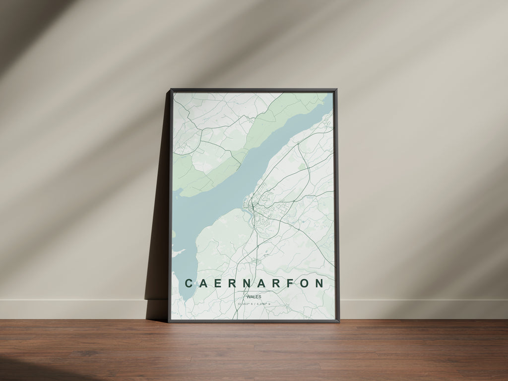 Caernarfon, Wales, United Kingdom map print in the Forest theme in a black frame on a wooden surface against a pale wall