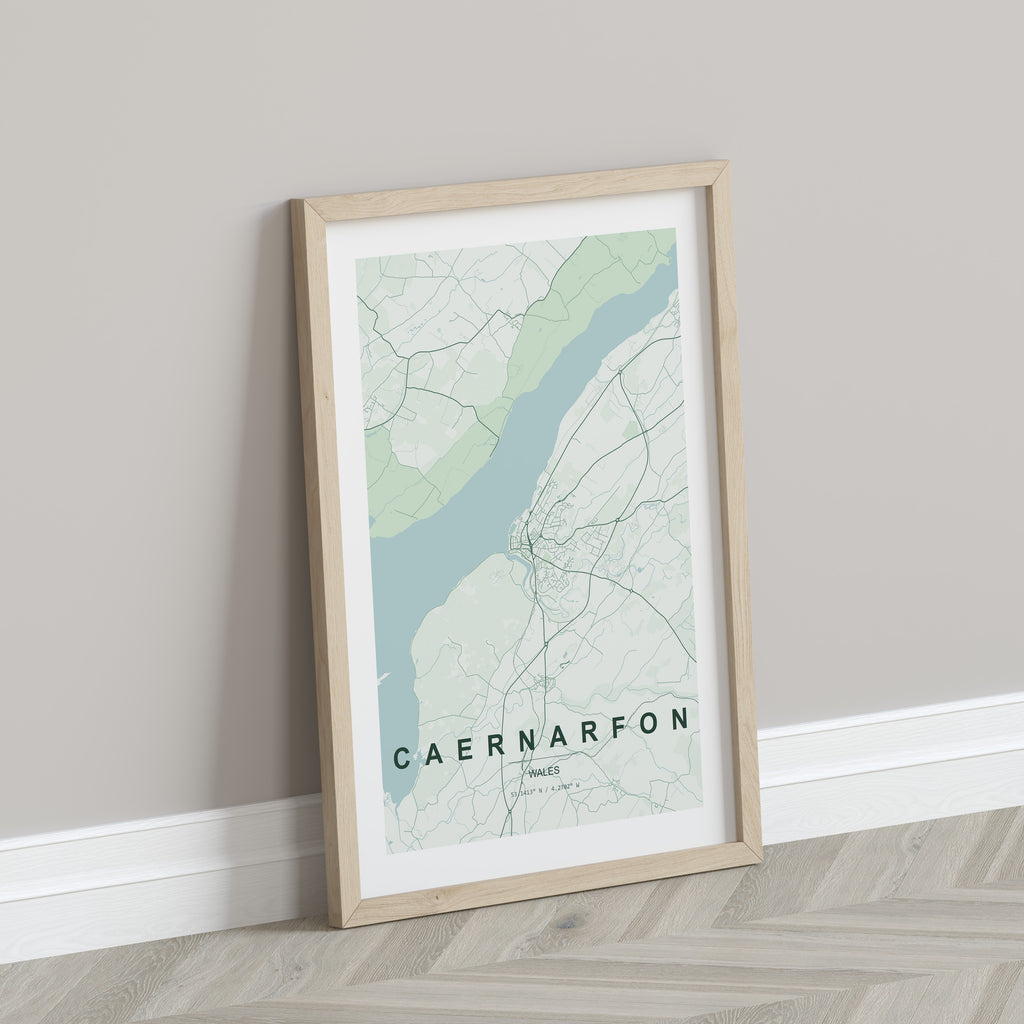 Caernarfon, Wales, United Kingdom map print in the Forest theme in a light wooden frame leaning against a pale wall