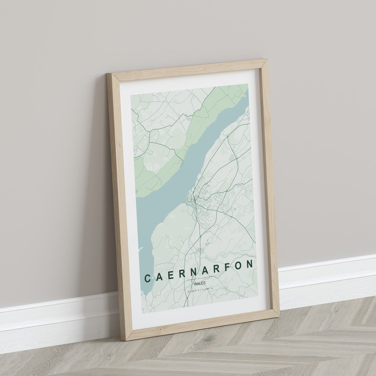 Caernarfon, Wales, United Kingdom map print in the Forest theme in a light wooden frame leaning against a pale wall