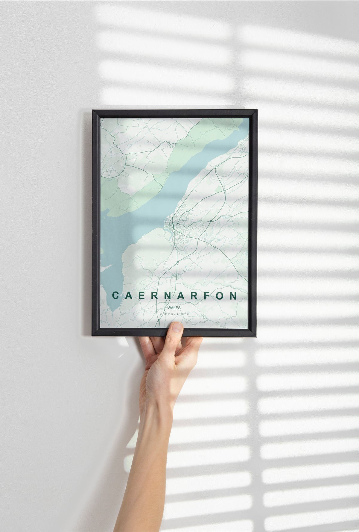 Caernarfon, Wales, United Kingdom map print in the Forest theme in a black frame held against a pale wall